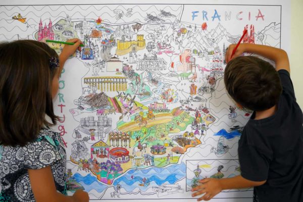 Dos niños pintando el mapa gigante de España para colorear de Pinta y Pinto