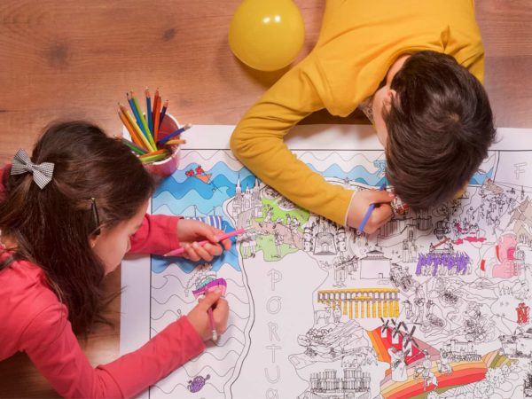 Detalle de niños en el suelo coloreando el mapa de España para colorear de Pinta y Pinto